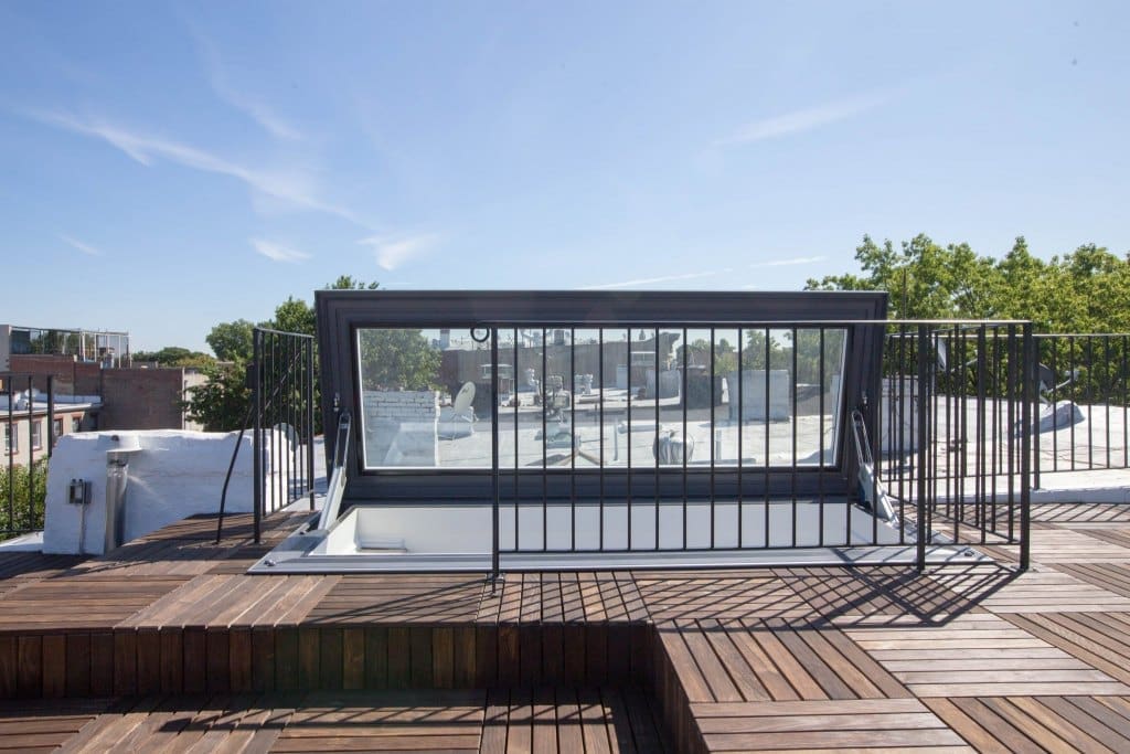 Skybox side-hinged skylight, fully open on a flat roof deck in New York.